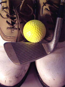Yellow golf ball beside brown leather shoe